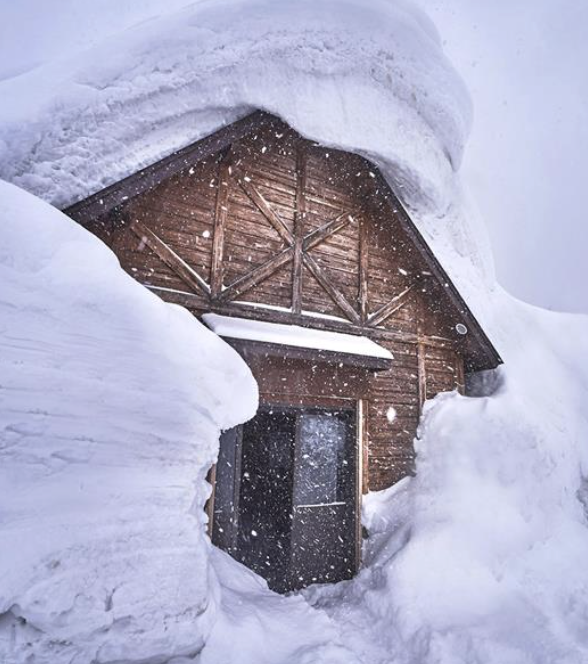 Heavy snow piled around a mountain cabin entry